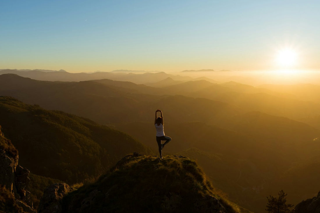 Yoga pose on a mountain summit at sunset — reduce stress with mindfulness and yoga